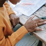 black woman touching screen of smartphone at table